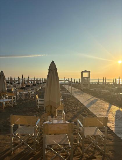 Spiaggia deserta all'alba, ombrelloni chiusi, atmosfera serena e luminosa.