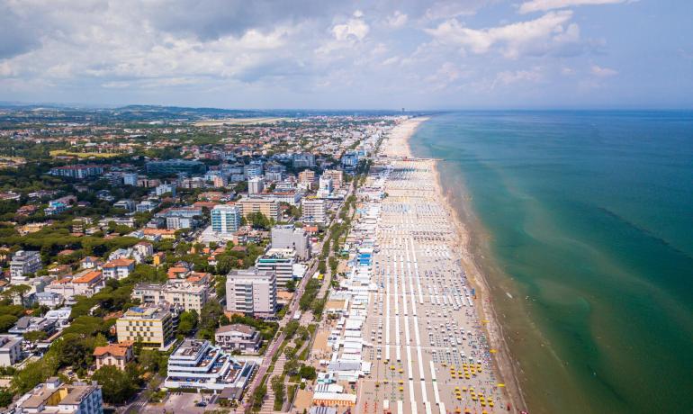 Vista aerea di una spiaggia affollata e città costiera.