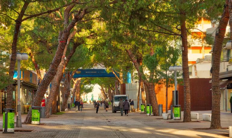 Strada alberata con persone che passeggiano a Riccione.