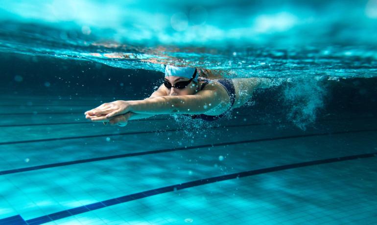Nuotatrice sott'acqua con bracciata potente in piscina.