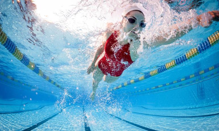 Nuotatrice in piscina, vista subacquea, costume rosso.