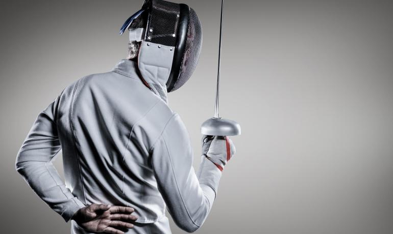 Scherma: atleta con maschera e spada in posa di attesa.