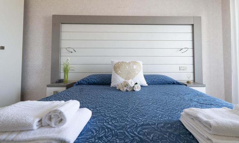 Camera da letto elegante con lenzuola blu e decorazioni floreali.