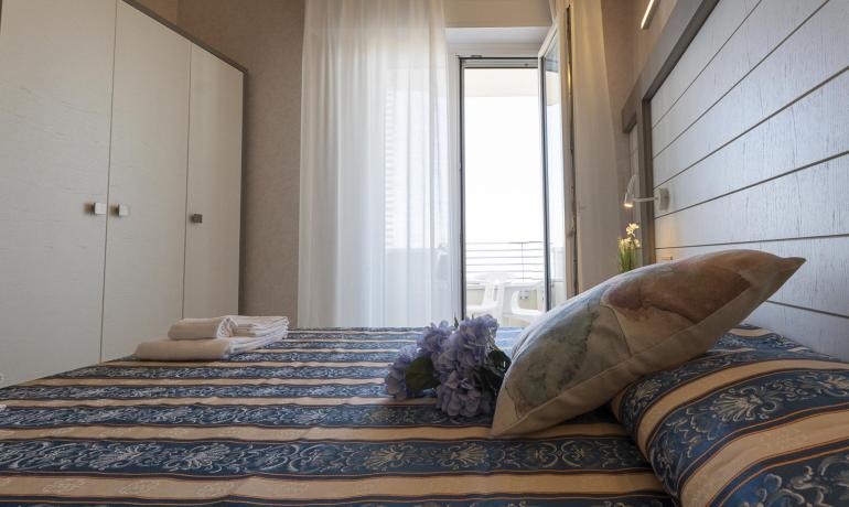 Camera elegante con letto decorato e balcone.
