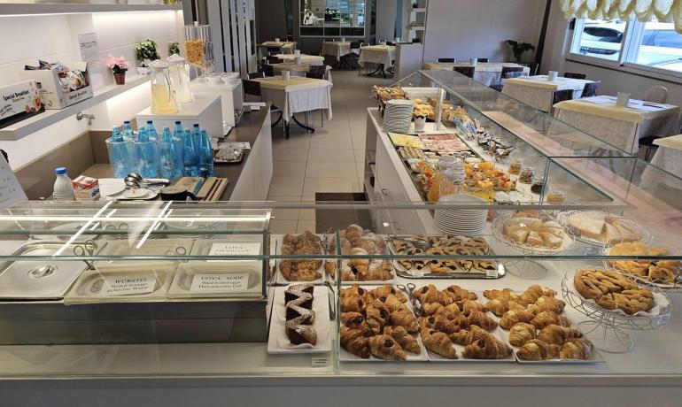 Elegante buffet di colazione con croissant, dolci e bevande in un ambiente raffinato.